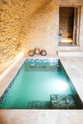 - une piscine dans une chambre dotée d'un mur en pierre dans l'établissement Chateau De Londigny & Spa Retreat, à Londigny