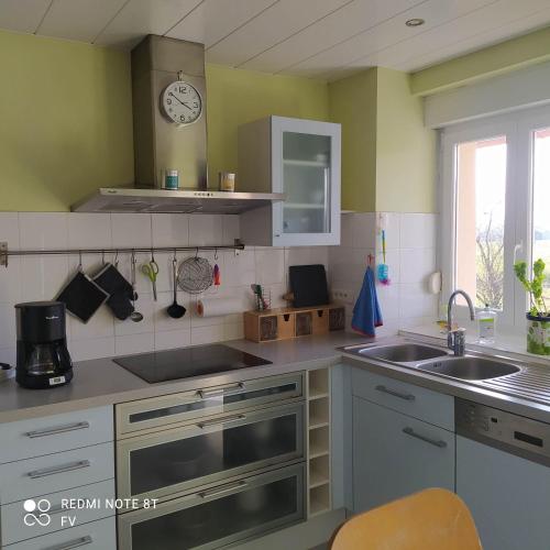 une cuisine avec un évier et une horloge murale dans l'établissement Gite de la combe, à Désandans