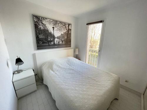 une chambre blanche avec un lit et une fenêtre dans l'établissement APPARTEMENT AVEC CHAMBRE ET CABINE SEPAREE À DEUX PAS DES PLAGES, au Cap d'Agde