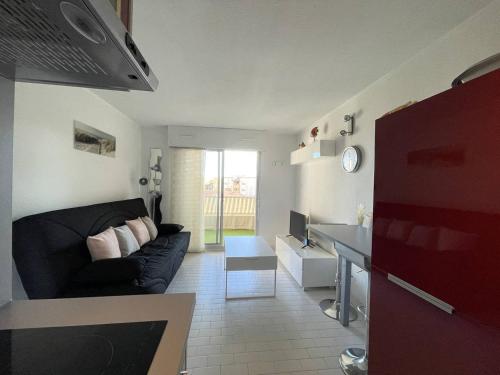 - un salon avec un canapé noir et un bureau dans l'établissement APPARTEMENT AVEC CHAMBRE ET CABINE SEPAREE À DEUX PAS DES PLAGES, au Cap d'Agde