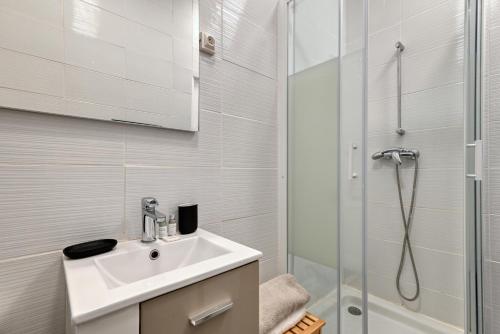 une salle de bain blanche avec un lavabo et une douche dans l'établissement La Bonne Mère plein cœur du vieux port, à Marseille