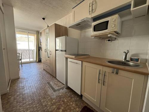une petite cuisine avec un évier et un micro-ondes dans l'établissement AGREABLE STUDIO CABINE DONNANT SUR TERRASSE AVEC VUE MER, au Cap d'Agde