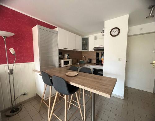 une cuisine avec une table, des chaises et une horloge dans l'établissement DEUX PIECES EN REZ DE CHAUSSEE A DEUX PAS DE LA PLAGE DU MOLE, au Cap d'Agde