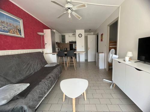 un salon avec un canapé et un ventilateur de plafond dans l'établissement DEUX PIECES EN REZ DE CHAUSSEE A DEUX PAS DE LA PLAGE DU MOLE, au Cap d'Agde