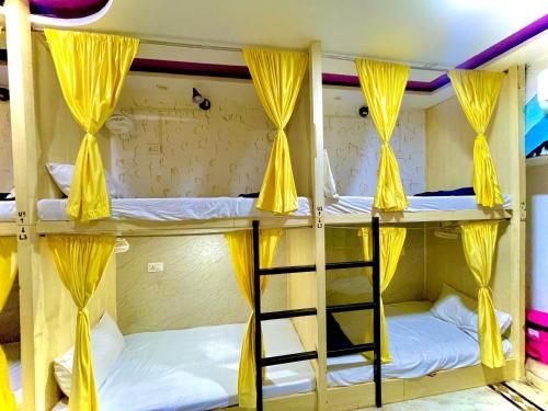 a group of bunk beds with yellow curtains and a ladder at COZY NEST Homestay & Rooftop Cafe in Agra