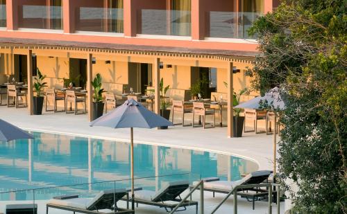 a hotel pool with chairs and tables and umbrellas at Alkyna Lifestyle Beach Resort - Adults Only in Agios Gordios