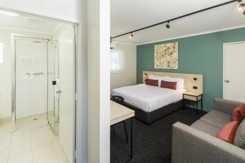 a hotel room with a bed and a shower at Nightcap At Balaclava Hotel in Cairns