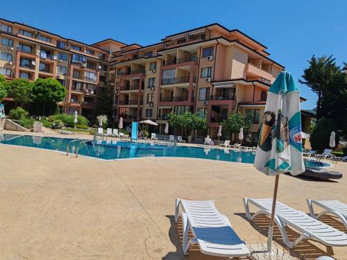 a pool with chairs and an umbrella and a hotel at Magic Dreams Apartments in Sveti Vlas