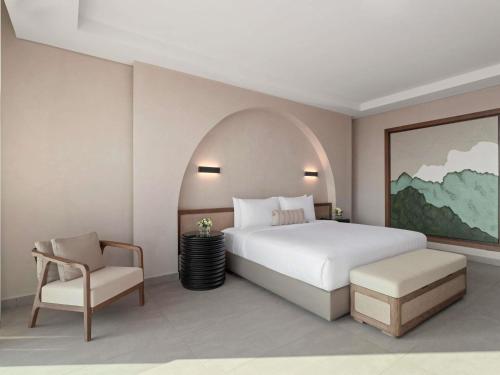a bedroom with a white bed and a chair at Rixos The Palm Hotel & Suites - Ultra All Inclusive in Dubai