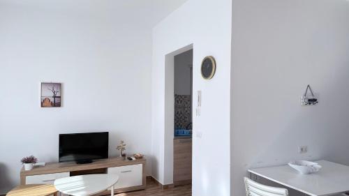 a white living room with a table and a television at Vala Mar Apartments by Four C in Hamallë
