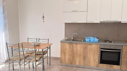 a kitchen with a table and a sink and a table and chairs at Vala Mar Apartments by Four C in Hamallë