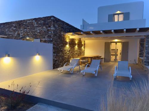 a patio with chairs and a table and a building at Farous seaside sunset villa II in Andiparos