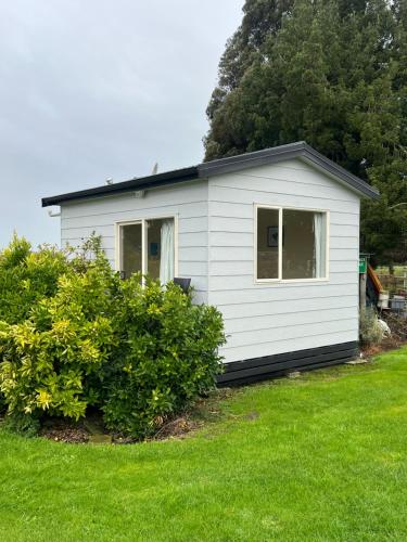 a small white house in a yard with green grass at Green Hayes Estate Rentals - Green Hayes Cabin in Temuka