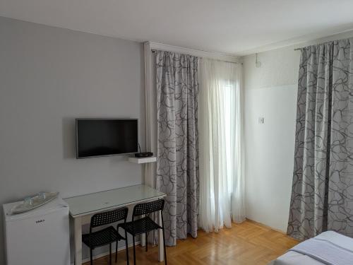 a room with a desk with two chairs and a television at Apartmani Abeona in Budva