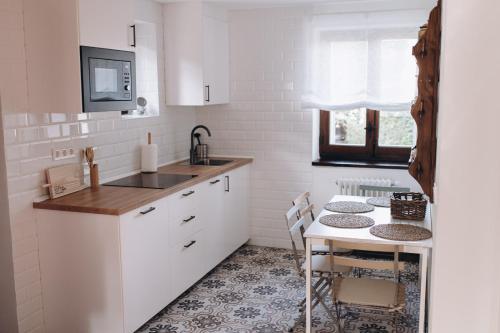 a kitchen with white cabinets and a table with a sink at EL MOTIVO in Cercedilla