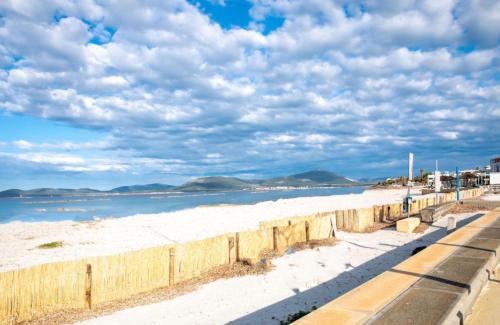 a beach with white sand and a wooden fence at La Casa di Lore & Leo in Alghero