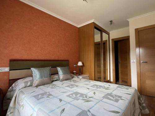 a bedroom with a large bed with an orange wall at El Mirador del Orfanato 1C in Llanes