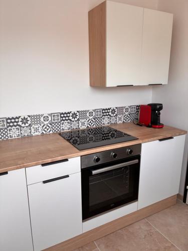 une cuisine avec des armoires blanches et un four à plaques de cuisson dans l'établissement L appartement du lac, à Briollay