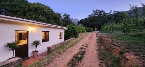 a dirt road next to a white building and a house at Sunkiss Cottage on Mount Joy Farm in Stellenbosch