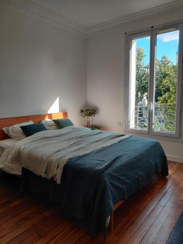 une chambre avec un grand lit et une grande fenêtre dans l'établissement Appartement design, parisien très lumineux, à Maisons-Alfort