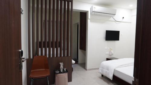 a bedroom with a bed and a chair and a tv at Anantha Shaiya in Tiruchchirāppalli