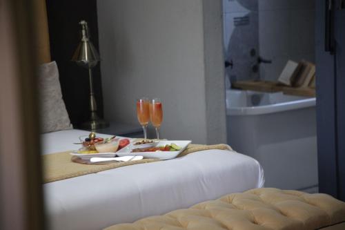 une chambre d'hôtel avec un plateau de nourriture et des verres à vin dans l'établissement The Village GuestHouse, à Acornhoek