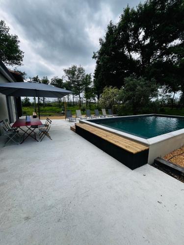 une piscine avec une table, des chaises et un parasol dans l'établissement La Casa M, à Sainte-Hélène