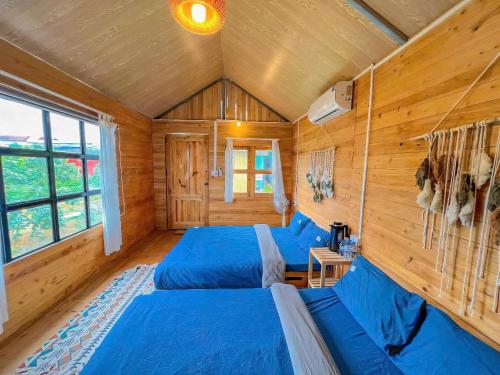 two beds in a room with wooden walls at Lacasa home&coffee Mộc Châu in Mộc Châu