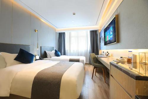 a hotel room with two beds and a desk at Weiting Hotel Shanghai Jing'an Temple Nanjing West Road Subway Station Branch in Shanghai