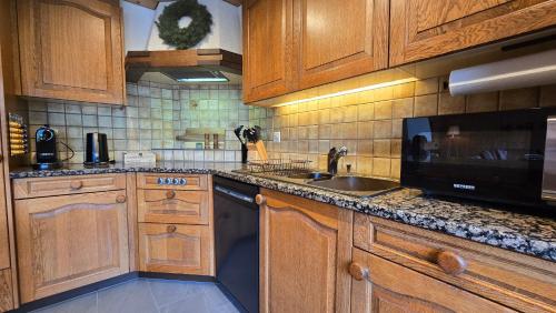 a kitchen with wooden cabinets and a sink and a microwave at Alpine Loft, Central, Balcony, Parking, Family,PS5 in Frutigen
