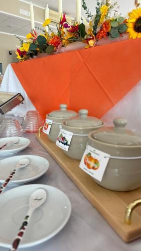 a table with three pots and plates and candles at Ibisco Hotel in Rodi Garganico