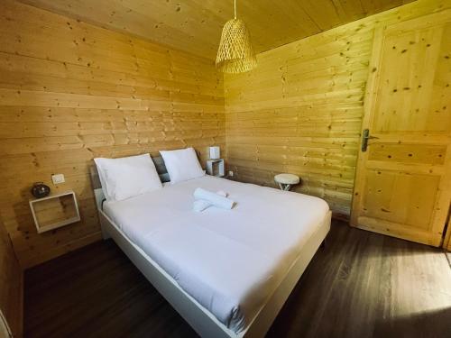 Cette chambre en bois comprend un grand lit blanc. dans l'établissement Bungal'eau, à Sciez