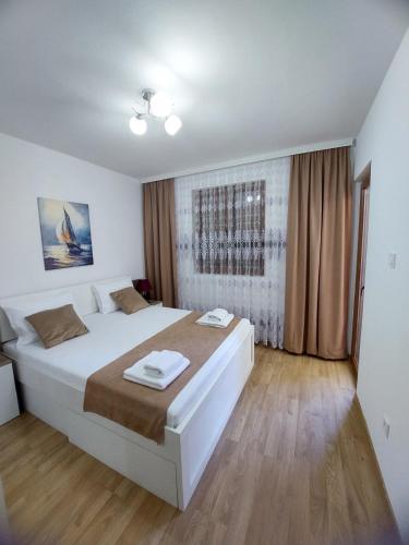 a bedroom with a large white bed and wooden floors at Jana apartment 3 in Tivat
