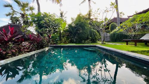 a swimming pool in a yard with trees at Frangipani Inn & Restaurant in Seraya