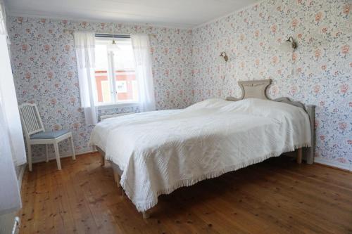 a bedroom with a white bed with floral wallpaper at Åsens By in Haurida