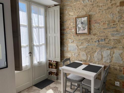une table et des chaises dans une pièce avec un mur en pierre dans l'établissement L'Orangerie, à Mouchamps