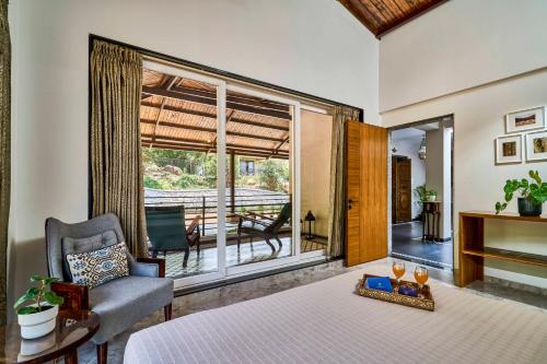 une chambre avec un lit et une chaise et un balcon dans l'établissement SaffronStays Blissfort, à Malavli