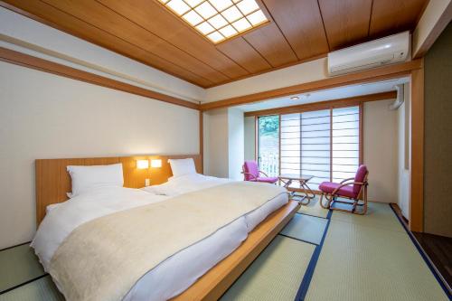 a bedroom with a large bed and two pink chairs at Kinugawa Onsen Hotel in Nikko