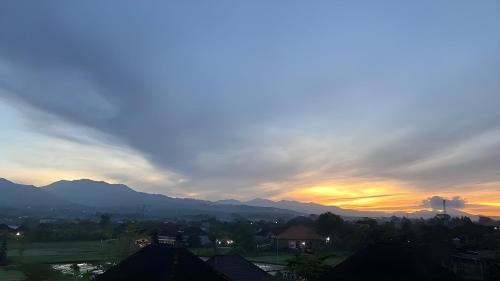 a sunset over a city with mountains in the background at Hotel Arda Bali in Negara