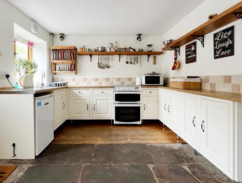 a kitchen with white cabinets and white appliances at Foresters Inn Cottage in Parkend