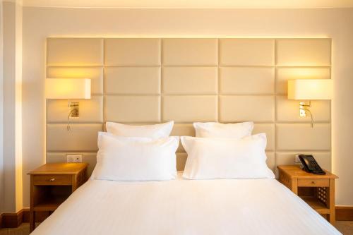 a bed with white pillows and two lamps and a phone at Best Western Premier Montfleuri in Sainte-Maxime
