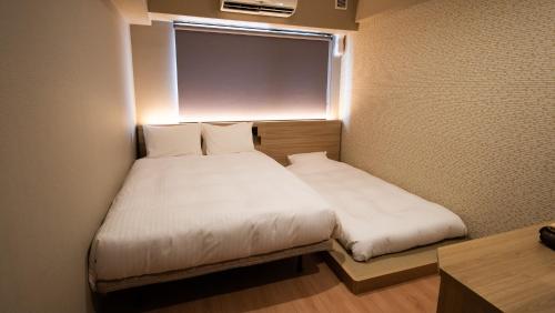 a small room with a bed and a window at HOTEL SANSUI NAHA Ryukyu Onsen Naminoue-No-Yu in Naha