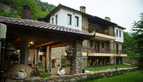 ein großes Steinhaus mit Balkon im Hof in der Unterkunft Archontiko Emmanouilidi Suites in Kato Loutraki