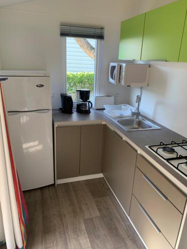 une cuisine avec un réfrigérateur blanc et un évier dans l'établissement Mobil home Bahia DUO Prenium, à Genouillé