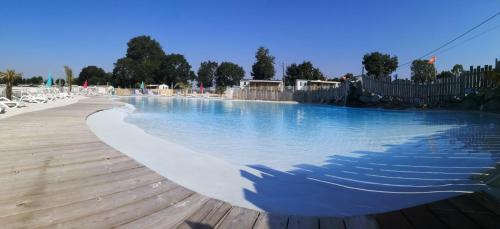 - une piscine avec de l'eau bleue et des chaises blanches dans l'établissement Mobil home Bahia DUO Prenium, à Genouillé