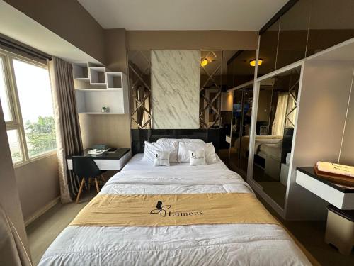 a hotel room with a large bed and a desk at Apartment Thematic Lumens at Margonda Residence in Kemirimuka Dua
