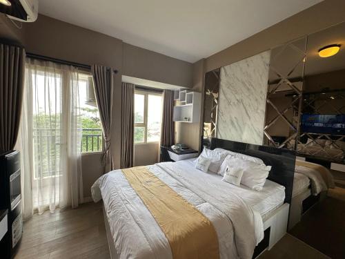 a bedroom with a large bed and a large window at Apartment Thematic Lumens at Margonda Residence in Kemirimuka Dua
