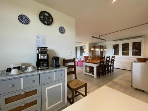 a kitchen and living room with a clock on the wall at Les Gîtes de La Maison Bleue d'Estialescq in Estialescq