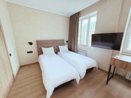アスタナにあるTan Hotel Astanaの大きな白いベッドとテレビのある寝室
