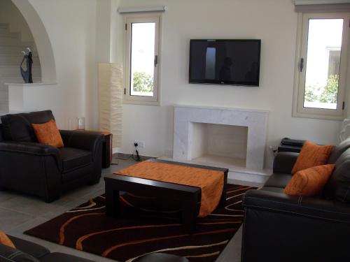 a living room with two couches and a fireplace at Aphrodite Sands in Mandria